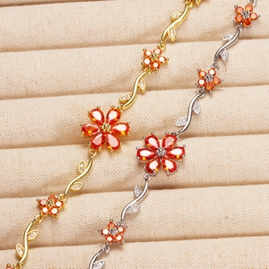 Macro detail of copper flower bracelet with orange zircon petals and vine leaves