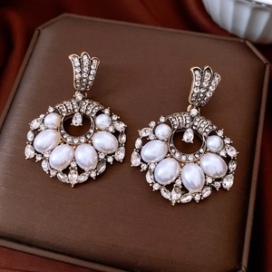 Detailed view of vintage gold earrings with large white pearls and sparkling rhinestones