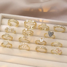 Close-up of golden stackable rings with heart and flower motifs in a velvet box