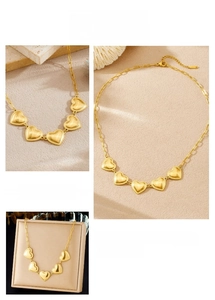 Detail of five gold heart charms on a linked chain with polished bead edges and lobster clasp