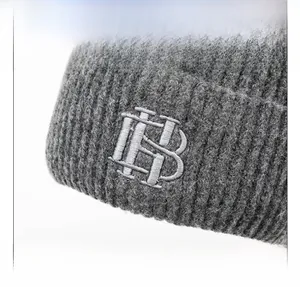 Détail du bonnet en maille grise avec broderie HB et texture en tricot côtelé