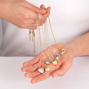 Handheld view of heart pendant necklaces in gold and silver with cubic zirconia accents