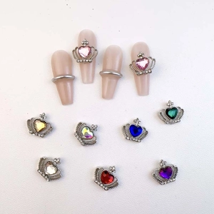 Macro shot of silver crown nail charms with colorful heart crystals for luxury nail art