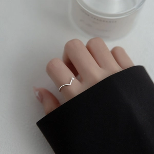 Detailed close-up of a silver V-shaped sparkling diamond ring worn on a model's finger