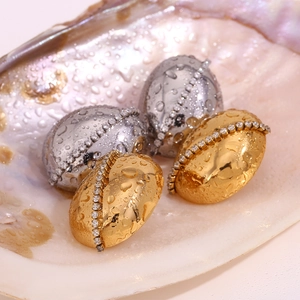 Macro shot of 18K gold and silver oval chain earrings with zircons in a shell