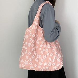 Detail of pink canvas shoulder bag featuring 3D floral lace texture worn by model
