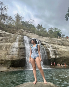 Detail of blue floral swimsuit with elegant bow tie shoulder straps near a waterfall