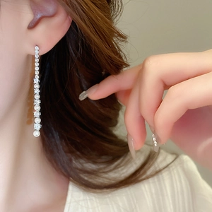 Détail de boucles d'oreilles pendantes en argent avec perles et zircons sur un mannequin