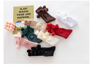 Detailed view of ribbed knit baby socks with pom-poms in 8 assorted autumn colors