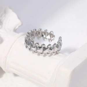 Close-up of a silver geometric spiked ring with adjustable open band on a white sculpture