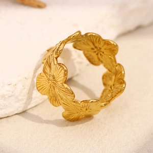 Macro detail of gold plated flower ring showing intricate carved petal textures and finish