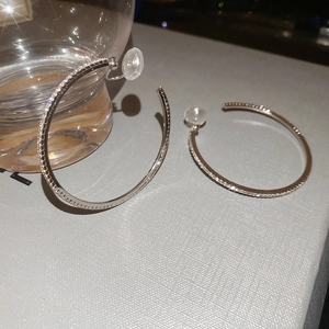 Macro detail of silver C-shaped hoop earrings with sparkling inset rhinestones and silicone back