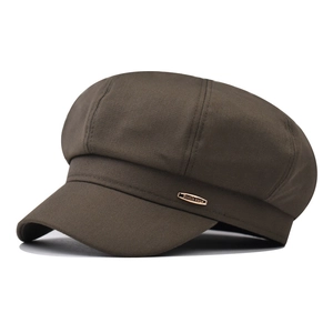 Detail of vintage brown newsboy cap with textured twill fabric and gold metal logo plate