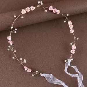 Macro detail of handmade bridal headband with pink flowers and pearls on gold wire
