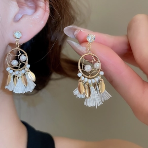 Detail of bohemian pearl dreamcatcher earrings with gold leaves and tassels on model