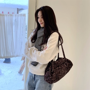 Dettaglio della borsa tote leopardata indossata con sciarpa a righe e felpa casual