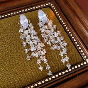 Macro view of crystal tassel earrings with marquise stones on green velvet background