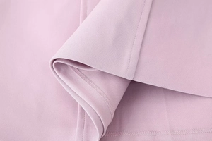 Detailed macro view of the dusty pink fabric texture and hem stitching on this mini dress