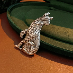 Makroaufnahme einer Vintage-Silber-Katzenbrosche mit geometrischer Textur auf Samt