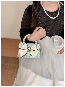 Detail of girls mini green houndstooth handbag with large pearl bow and elegant handle