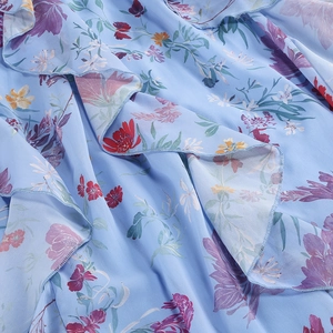 Nahaufnahme von hellblauem floralem Chiffon-Stoff mit mehrlagigem Rüschensaum
