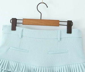 Close-up of mint blue pleated mini skirt showing detailed textured fabric and waist folds