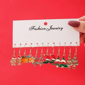 Detail of Christmas earring set featuring gingerbread man and bell on red card