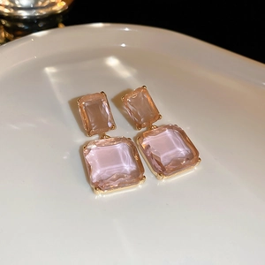 Detail of champagne pink rectangular crystal earrings with double-layered gold geometric drops