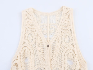 Dettaglio gilet all'uncinetto con ricami floreali traforati e bottone in legno