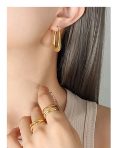 Detail of 18k gold plated U-shaped earring and minimalist rings on female model