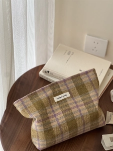 Detailed view of vintage plaid tweed texture and woven label on checkered cosmetic bag