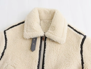 Detail of cream fleece collar featuring black leather trim and metal zipper on the jacket