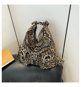 Detailed close-up of leopard print fabric with silver zippers on a brown tote bag