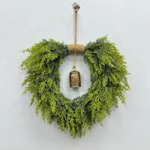 Close-up of heart-shaped cedar Christmas wreath with rustic metal bell and twine