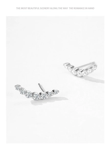 Macro shot of silver curved stud earrings featuring multiple inlaid clear zircons