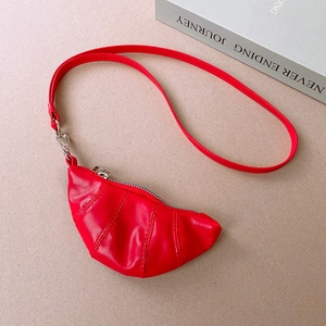 Detail of red faux leather croissant pendant with stitching and silver zipper closure