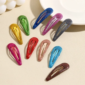 Set of 10 colorful glitter teardrop BB hair clips for children on a beige textured background