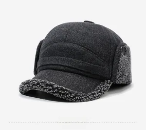 Close-up of thick grey winter hat with warm faux shearling earflaps and metal sports logo