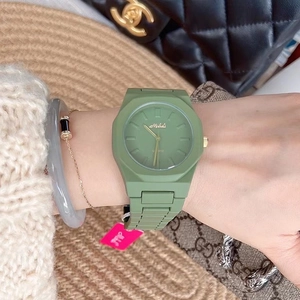 Close-up of green silicone quartz watch worn with bracelets and a luxury scarf