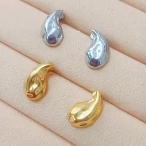 Close-up of polished 18K gold and silver teardrop earrings in a pink jewelry box