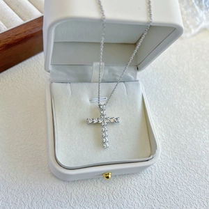 Detail of a sparkling silver cross necklace with zircons displayed in a white jewelry box