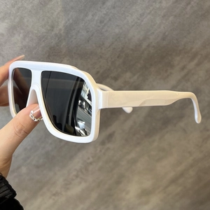Close-up side view of white oversized sunglasses with broad temple design and grey lenses
