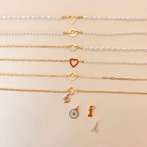 Detail van barokke parels en gouden kettingen met hartsluiting en letterhangers