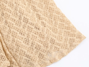 Macro shot of beige hollow knitted fabric showing detailed diamond grid texture