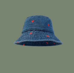 Detail view of heart embroidery on dark blue denim bucket hat with red stitching