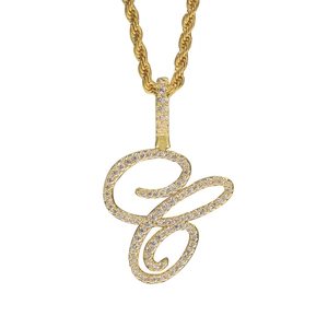Macro view of iced out cursive C pendant with cubic zirconia on a gold rope chain