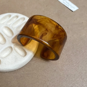 Detailed macro view of amber resin open ring with vintage tortoiseshell marble patterns