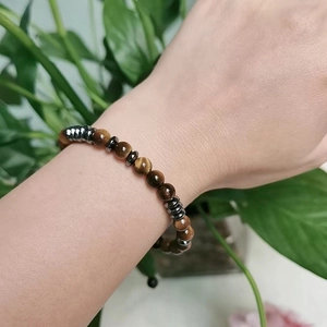 Close-up of tiger eye stone bead bracelet with hematite spacers on a male wrist