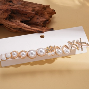 Dettaglio di un set da 12 orecchini con perle e strass su sfondo di legno naturale