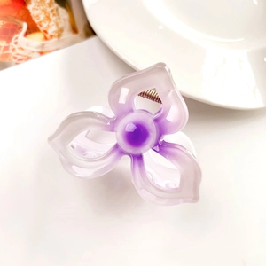 Detail of purple frangipani hair claw clip with gradient petals and golden spring